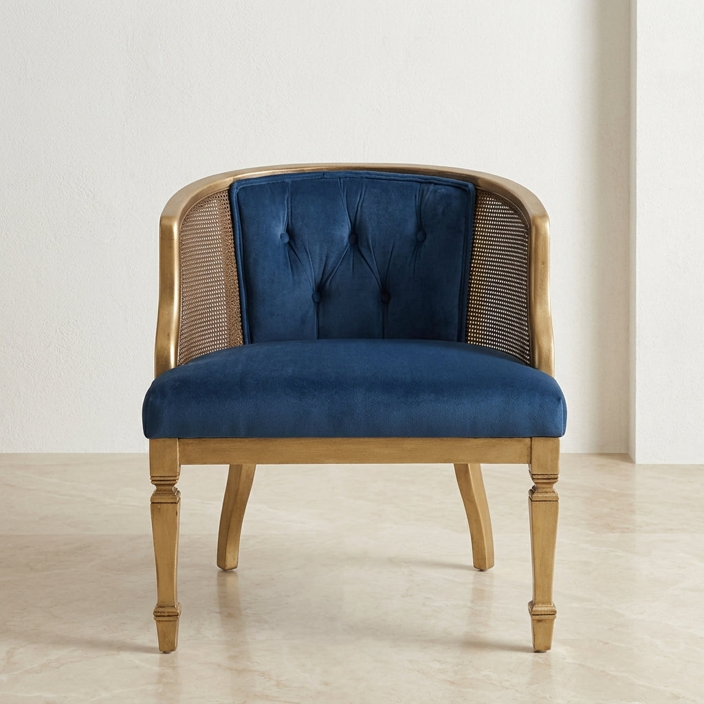 A classic-style accent chair with a deep blue velvet seat and back cushion, flanked by woven cane panels and framed in a light natural wood, set against a neutral cream wall and floor.