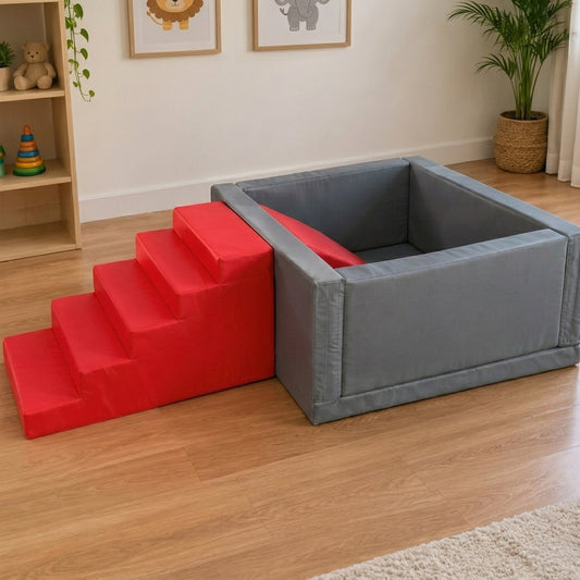 A gray rectangular pet playpen with an attached red four-step ramp, placed on a light wood floor in a child's room with framed animal art, a shelf, and a potted plant.