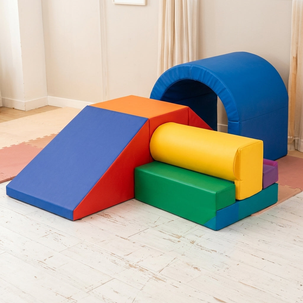A colorful children's foam play gym set with a blue tunnel, ramp, blocks, and a yellow cylindrical cushion, placed on a light wood floor in a room with cream walls and curtains.