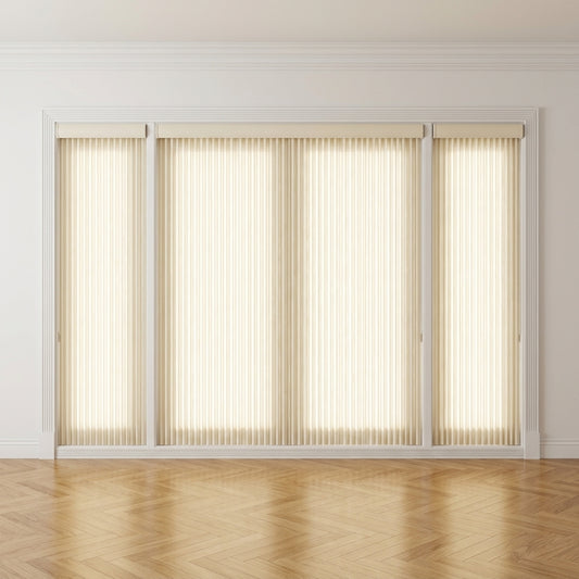 A set of beige vertical blind roller shades installed on a large window or sliding glass door in a bright room with light walls and a herringbone wood floor.