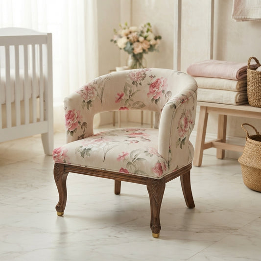 A vintage-style upholstered accent chair with a pink and green floral pattern on a cream fabric, set in a softly lit nursery next to a white crib.