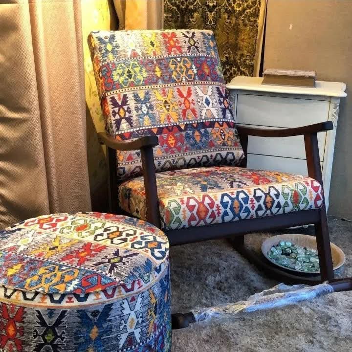 A mid-century modern accent chair with a colorful geometric kilim patterned fabric, paired with a matching round ottoman in a home setting.